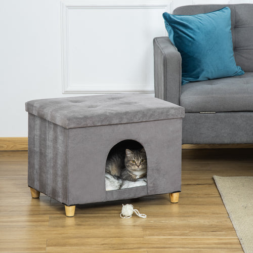 En multifunktionell grå kattgrotta som även fungerar som en fotpall, med en katt som vilar på den mjuka innerdynan.