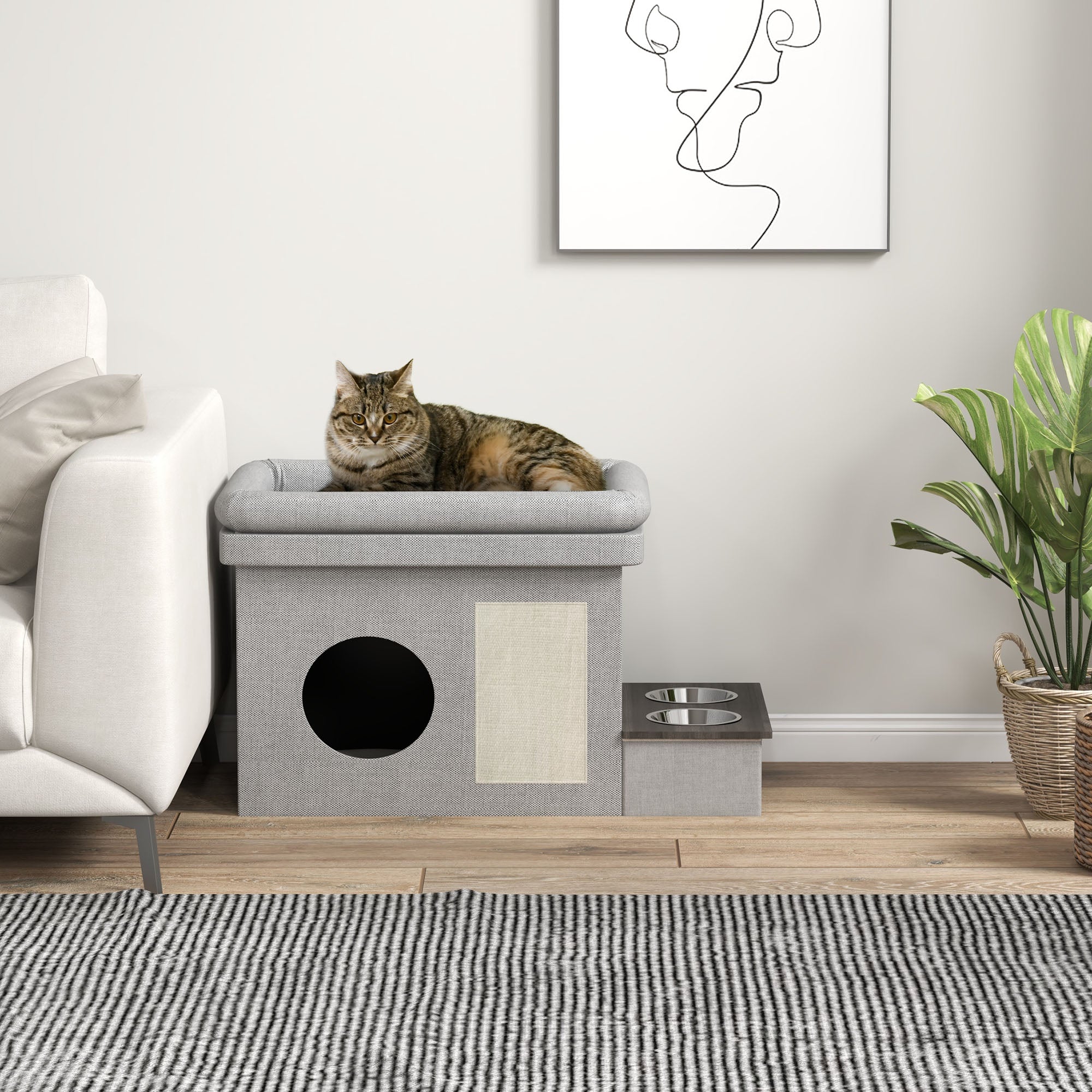 Ett elegant grått och cremévitt katthus för inomhusbruk med integrerad matstation, placerat bredvid en ljus soffa med en vilande katt på den övre nivån.