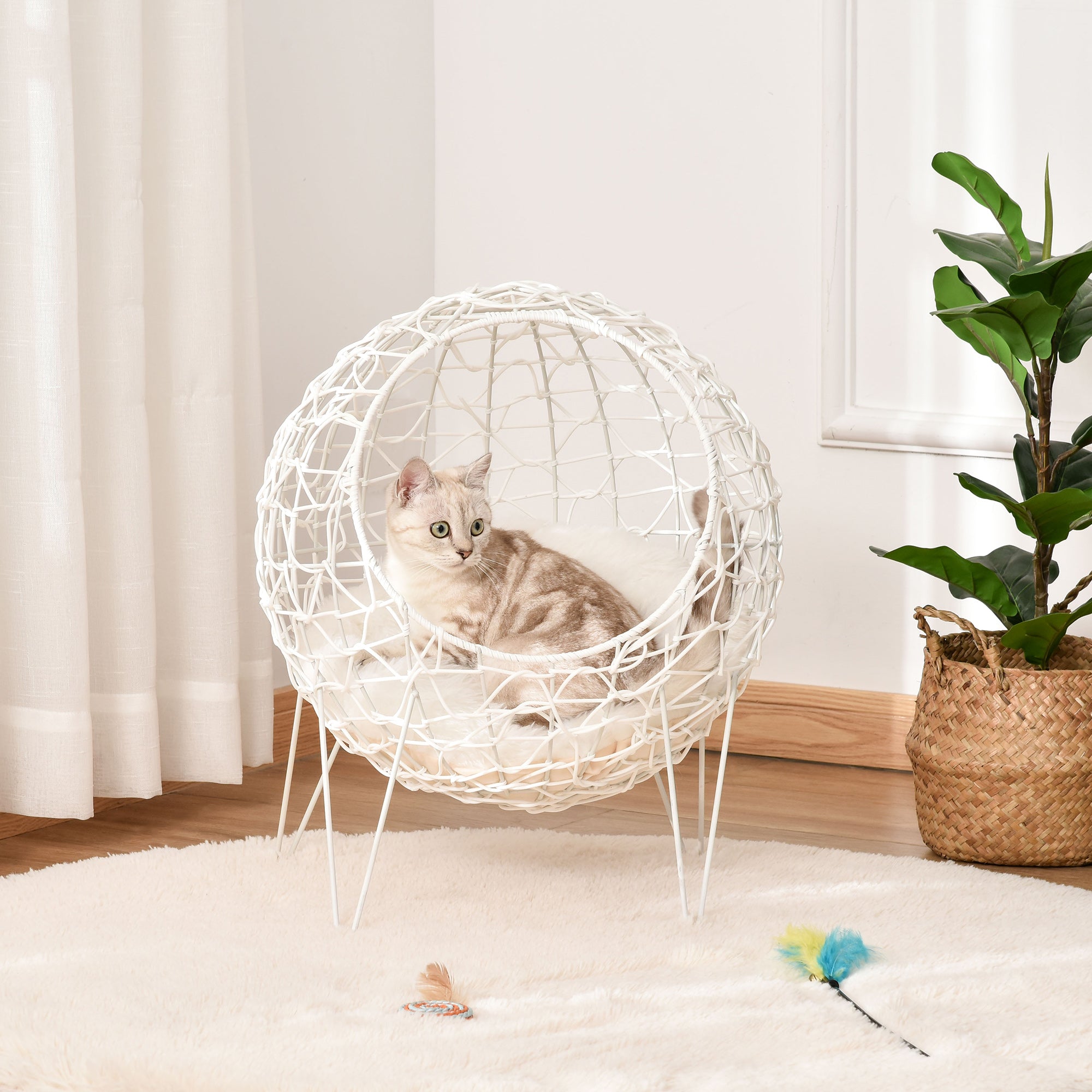 En lyxig vit rund kattkorg i flätad PE-rotting med en mjuk cremevit dyna och en katt som vilar inuti.