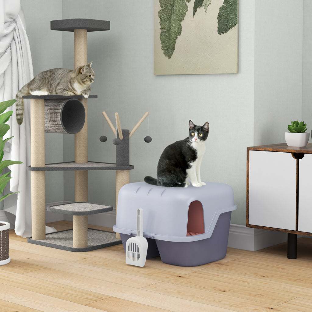 En svartvit katt står bredvid en stilren lila och grå halvöppen kattlåda med integrerad sandfångare ir medföljande spade.