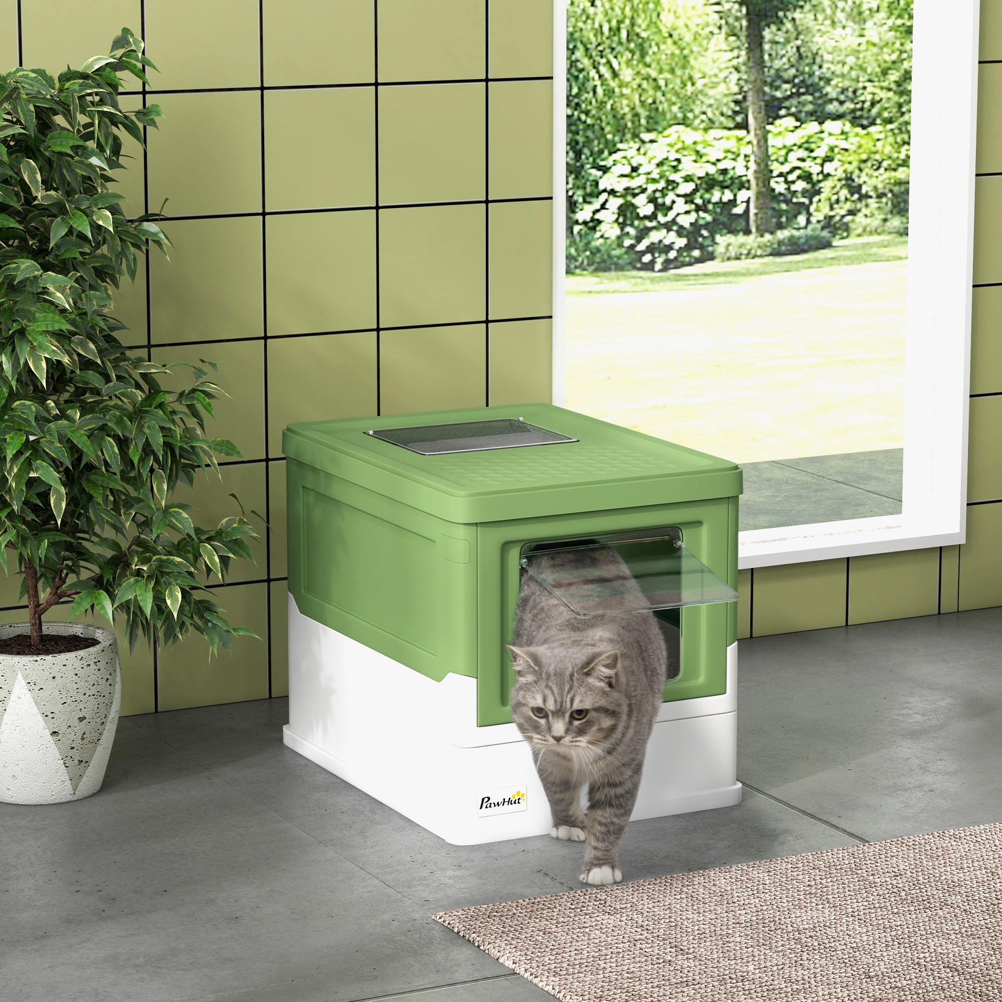 En grå katt står framför en smart stängd grön och vit kattlåda, placerad i ett rum med grönt kakel på väggen.