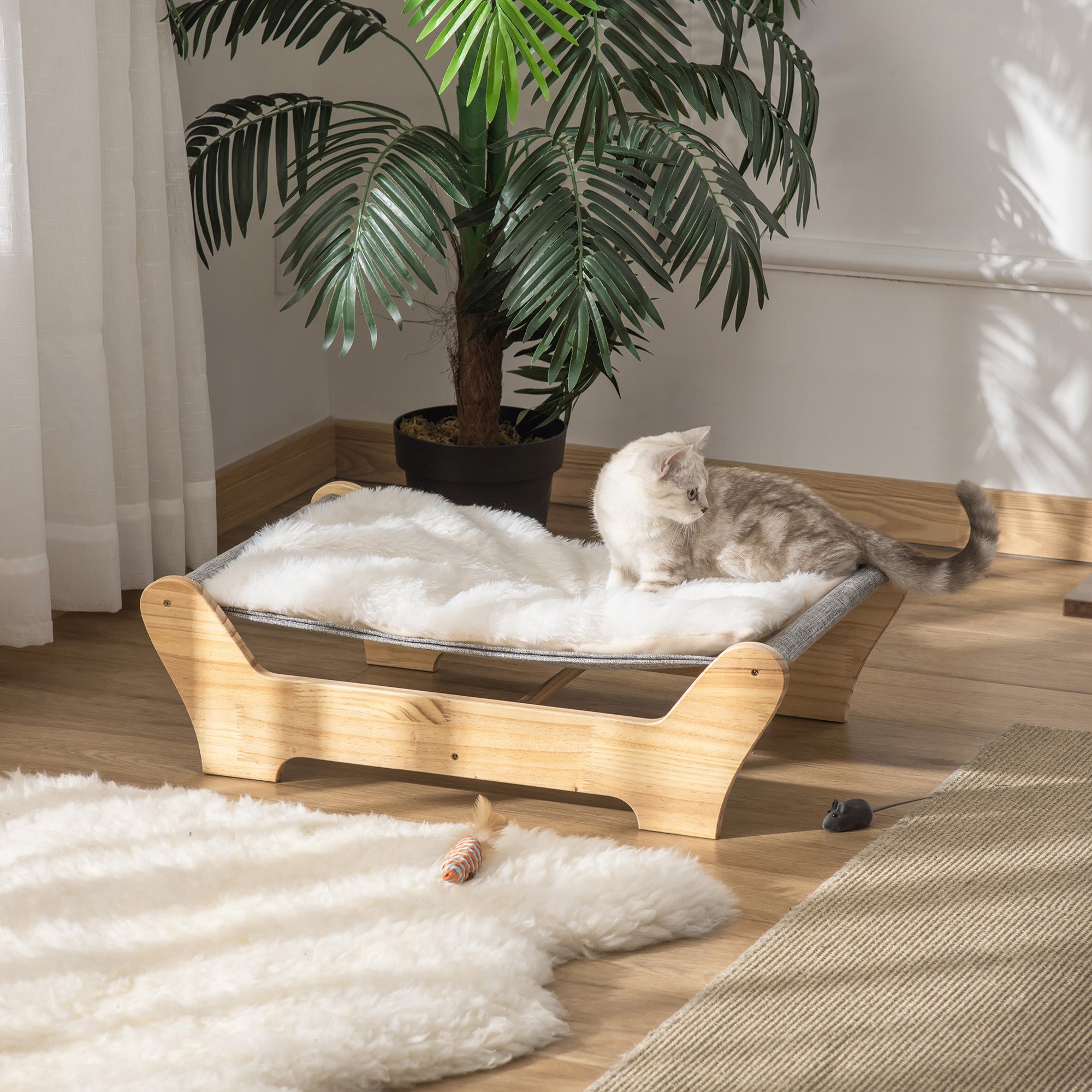 En stilren kattbädd i massivt furuträ med en mjuk ljusgrå dyna och en katt som vilar.