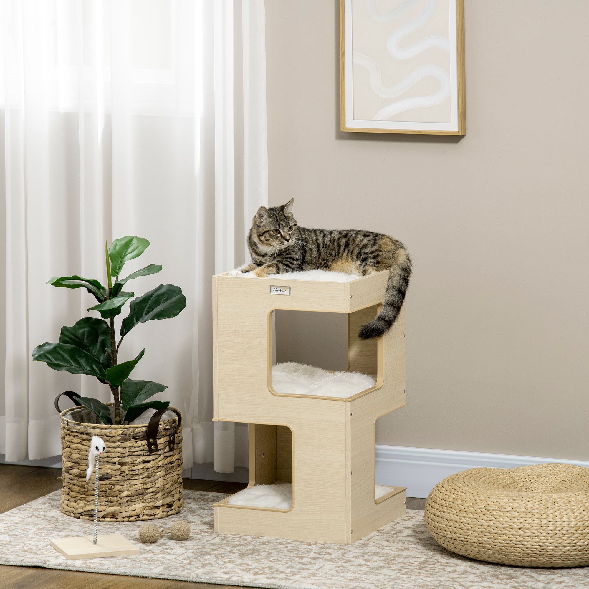 En modern kattgrotta i ekfinish med tre nivåer, mjuka ljusgrå kuddar och en leksaksmus placerad i ett stilrent hem.