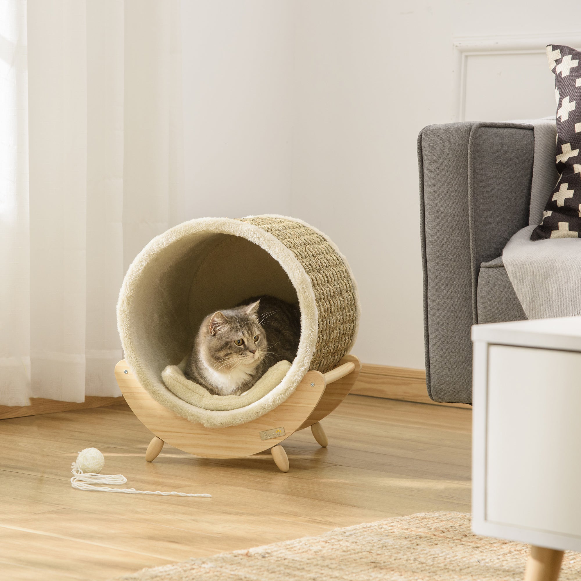 En modern cylinderformad kattgrotta i naturmaterial med en mjuk dyna och en katt som vilar inuti.