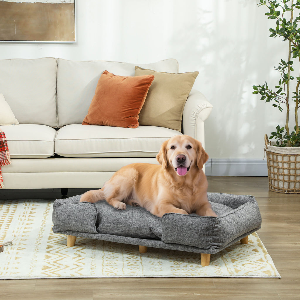 Stilren mörkgrå hundsoffa med ben i naturträ placerad i ett vardagsrum med en vilande Golden Retriever
