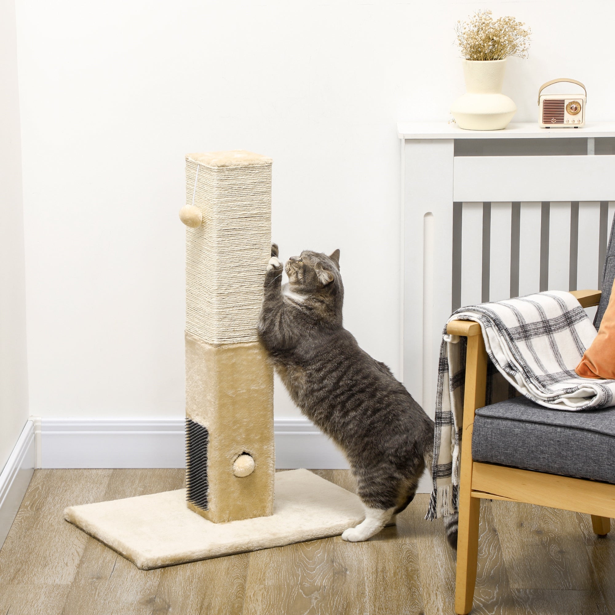 En grå katt sträcker sig för att klösa på en multifunktionell beige klöspelare utrustad med massageborstar och leksaker, placerad i ett hem.