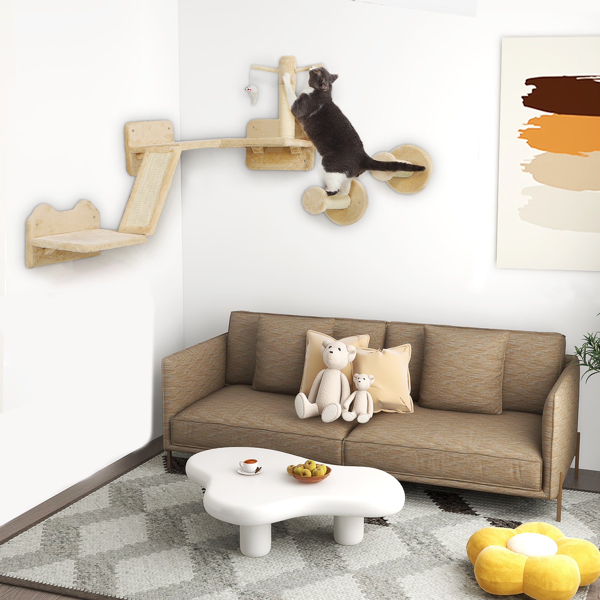 En svartvit katt klättrar på ett beige väggmonterat klätterset i tre delar, monterat på en vit vägg ovanför en soffa i ett modernt vardagsrum.